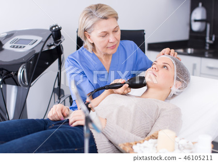 Cosmetician performing hardware face treatment 46105211