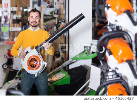 Smiling guy deciding on best leaf blower in garden equipment shop Smiling guy deciding on best leaf blower in garden equipment shop 46105427