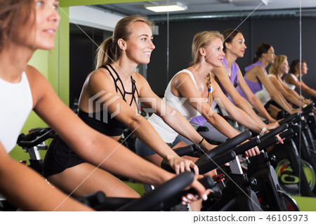 Women cycling in fitness center Women cycling in fitness center 46105973