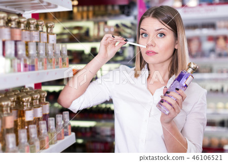 Woman smelling perfume testers in cosmetics showroom Woman smelling perfume testers in cosmetics showroom 46106521