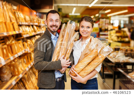 couple is standing with purchases in bread department couple is standing with purchases in bread department 46106523