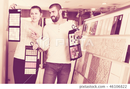 Positive couple holding sample of kitchen ceramic tile in modern store Positive couple holding sample of kitchen ceramic tile in modern store 46106822