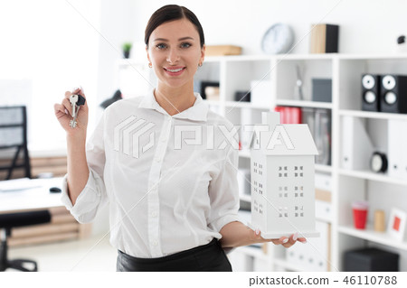 A young girl standing in the office and holding the keys and the layout of the house. A young girl standing in the office and holding the keys and the layout of the house. 46110788
