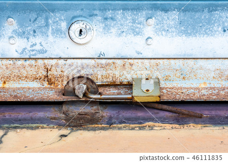 Old padlock on a rolling shutter door Old padlock on a rolling shutter door 46111835