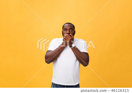 Amazed young African American hipster wearing white t-shirt holding hands in surprised gesture Amazed young African American hipster wearing white t-shirt holding hands in surprised gesture 46116323