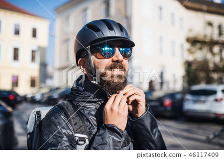 Male courier with sunglasses delivering packages in city. 46117409