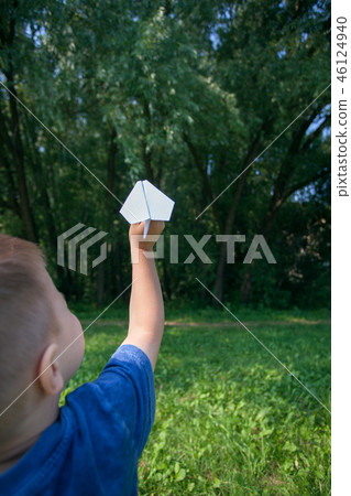 Paper airplane in children hands on greenery Paper airplane in children hands on greenery 46124940