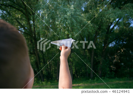 Paper airplane in children hands on greenery Paper airplane in children hands on greenery 46124941
