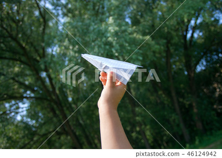 Paper airplane in children hands on greenery Paper airplane in children hands on greenery 46124942