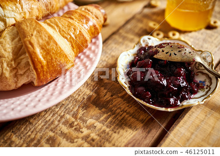 healthy morning breakfast with two croissants and marmalade on wooden table 46125011