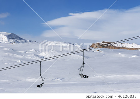 Snowy slope, chair-lift and blue sky with clouds 46126835
