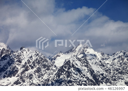 Snowy rock mountains in clouds at sun winter day Snowy rock mountains in clouds at sun winter day 46126997