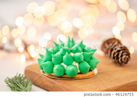 Mini mousse pastry dessert with green meringue. Garland lamps bokeh on background. Modern european Mini mousse pastry dessert with green meringue. Garland lamps bokeh on background. Modern european 46129755