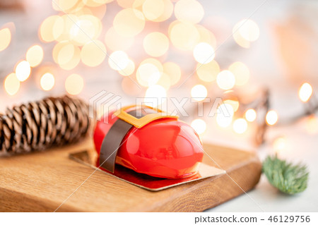 Mini mousse pastry dessert with red glazed on garland lamps bokeh background. Modern european cake Mini mousse pastry dessert with red glazed on garland lamps bokeh background. Modern european cake 46129756