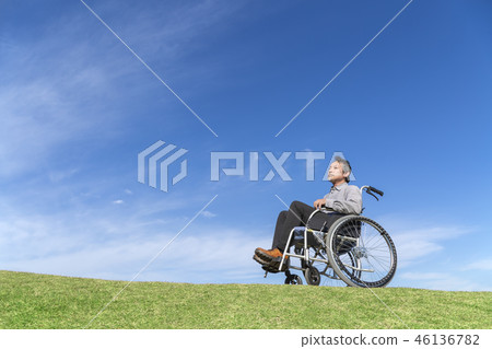 坐在輪椅的老人反對藍天背景。福利,護理,疾病,殘疾人,晚年的形象 坐在輪椅的老人反對藍天背景。福利,護理,疾病,殘疾人,晚年的形象 46136782