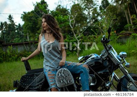 A woman sitting on a bike near fantastic landscape, jungle, tropical forest in front of her and the A woman sitting on a bike near fantastic landscape, jungle, tropical forest in front of her and the 46136784