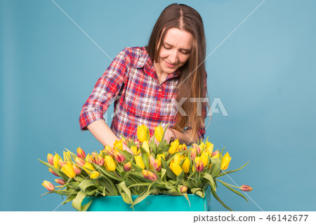 Charming female florist sorts out tulips in the box, selects them for the future flower arrangement Charming female florist sorts out tulips in the box, selects them for the future flower arrangement 46142677