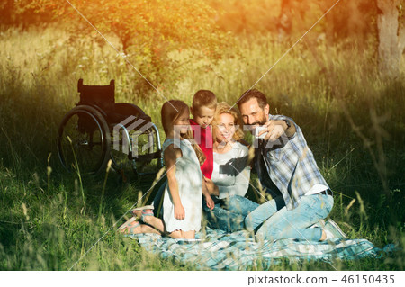 Happy family taking selfie on the picnic in park. Paraplegic 46150435
