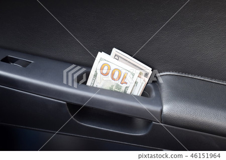 Several notes of US dollars and are folded in half in the door handle of the car. The money in the 46151964