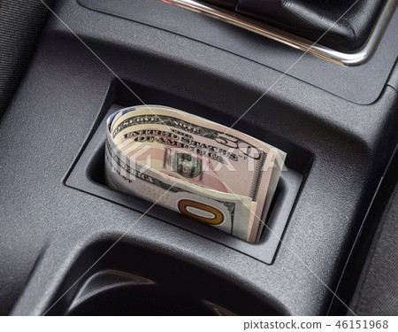 Several banknotes American dollars lie in the niche of the central console of the car. The money in Several banknotes American dollars lie in the niche of the central console of the car. The money in 46151968