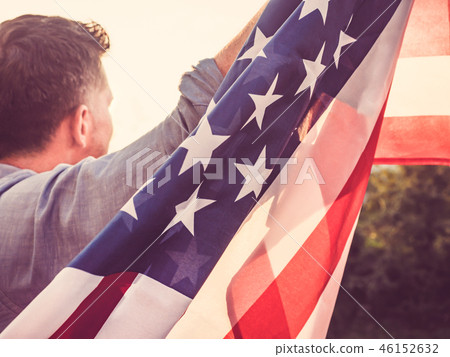 Attractive man holding waving in the wind US flag 46152632
