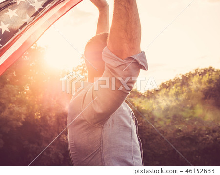 Attractive man holding waving in the wind US flag 46152633