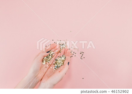 Woman hands covered golden stars confetti on pink 46152902