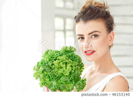 Young cute smiling girl holding organic green leaf lettuce near the face. Healtlife concept. 46153140