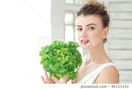 Young cute smiling girl holding organic green leaf lettuce near the face. Healtlife concept. 46153142
