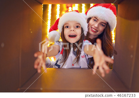 Merry Christmas and Happy Holidays Cheerful mom and her cute daughter girl opening a Christmas Merry Christmas and Happy Holidays Cheerful mom and her cute daughter girl opening a Christmas 46167233