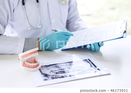 Male doctor or dentist working with report and patient tooth x-r Male doctor or dentist working with report and patient tooth x-r 46173931