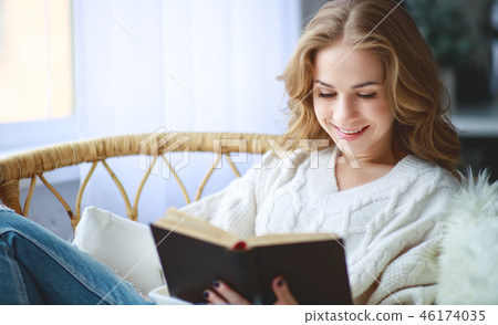 happy young woman reading a book by window 46174035