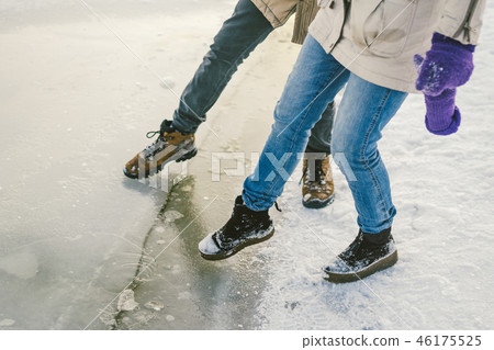 Trying the danger of the foot, testing the thin ice near the shore. A pair of lovers walk with a 46175525