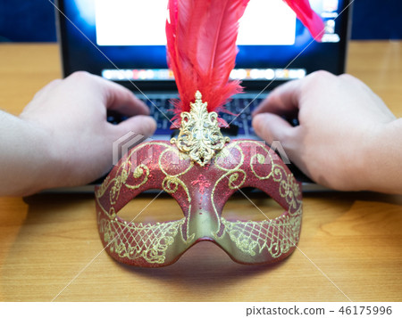 mans hands typing on laptop behind face mask 46175996
