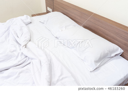 Messy bed. White pillow with blanket on bed unmade Messy bed. White pillow with blanket on bed unmade 46183260