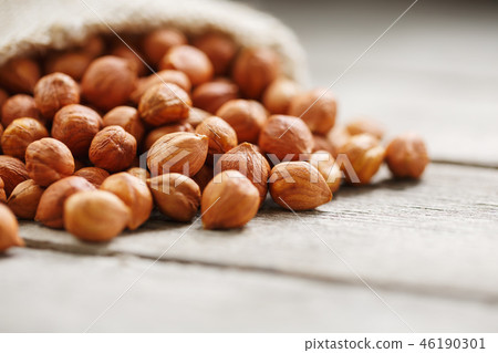 Chiselled hazelnuts in a bag of burlap on a gray Chiselled hazelnuts in a bag of burlap on a gray 46190301
