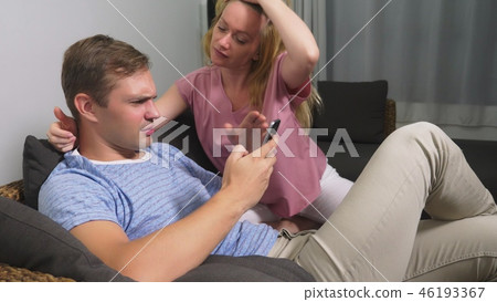 Couple crisis. Man and woman spend the evening in the living room on the couch. a man uses his phone 46193367