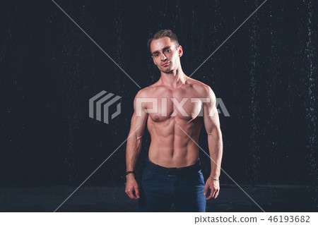 Fresh portrait of muscular man with water splashes on dark background. 46193682