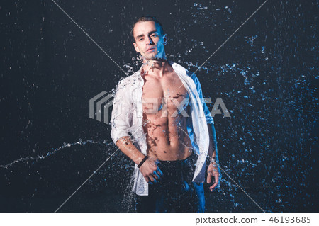 Fresh portrait of muscular man with water splashes on dark background. 46193685