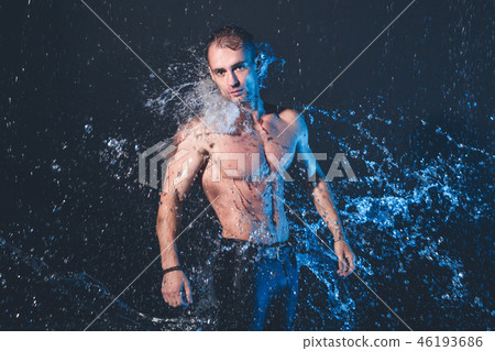 Fresh portrait of muscular man with water splashes on dark background. 46193686