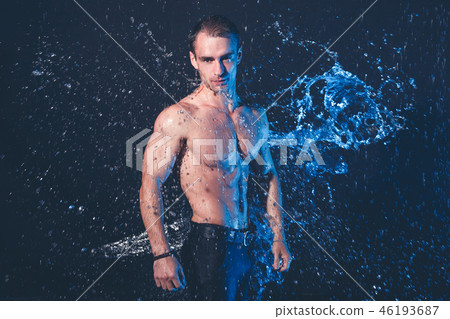 Fresh portrait of muscular man with water splashes on dark background. 46193687