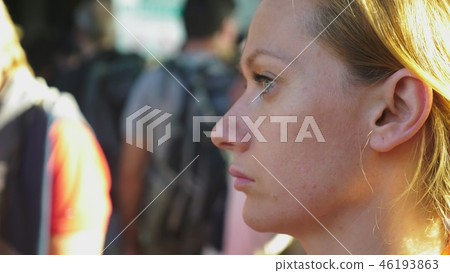 A tired woman rides on a bus while standing and holding onto a rail 46193863