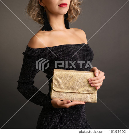 Young woman holding a golden clutch  46195602