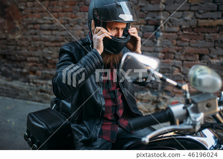 Biker puts on helmet before riding on chopper Biker puts on helmet before riding on chopper 46196024