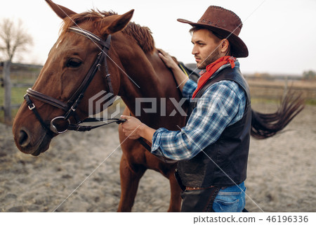 Cowboy poses with horse on texas ranch, wild west Cowboy poses with horse on texas ranch, wild west 46196336