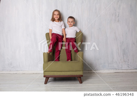 little boy and girl are brother and sister sit on a green Chair 46196348