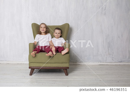 little boy and girl are brother and sister sit on a green Chair 46196351