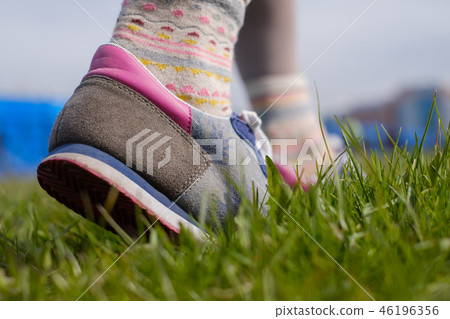 The girl is walking along the green grass The girl is walking along the green grass 46196356