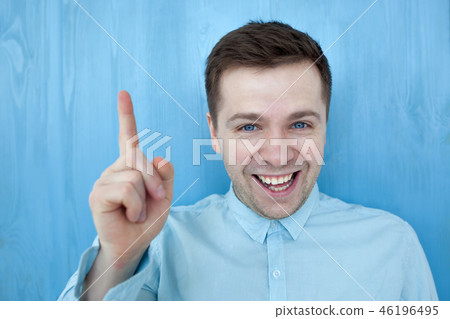 Satisfied young man showing index finger up 46196495