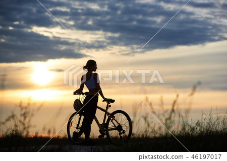 Woman posing near bike and enoying nature. Woman posing near bike and enoying nature. 46197017